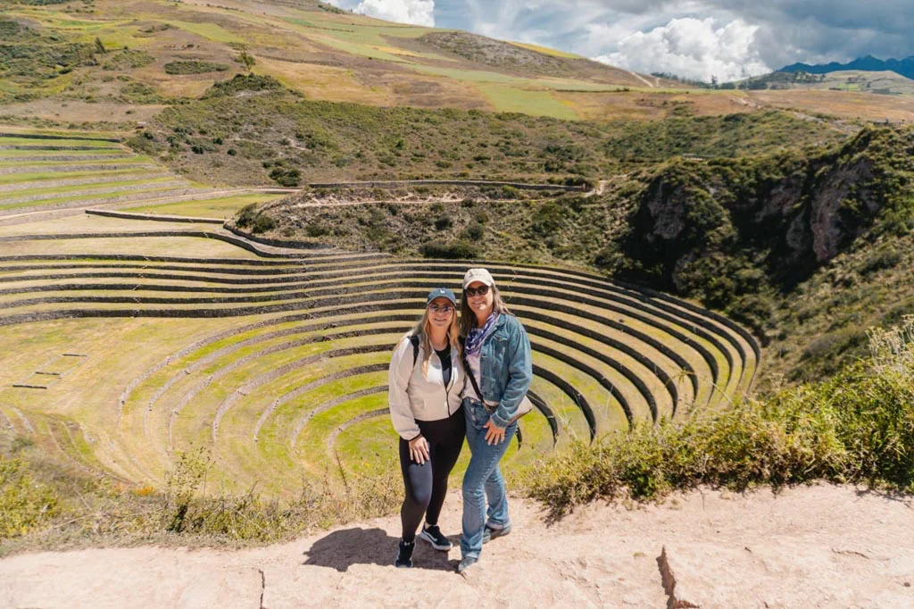 Two tourists visiting the circular Inca terraces at Moray in Peru